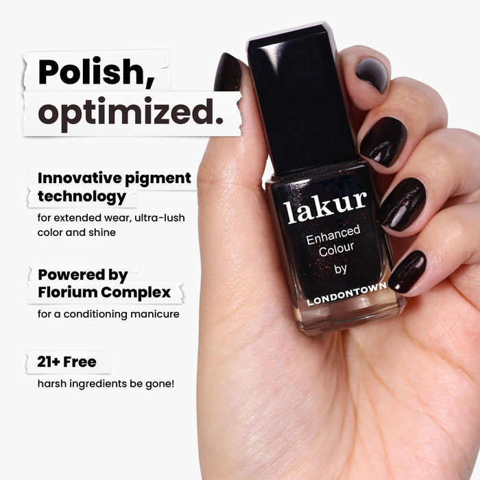 A hand holds a bottle of deep brown nail polish labeled "Around the Fireplace" by LONDONTOWN. This copper-flecked beauty offers innovative pigment and Florium Complex, free from 21+ harsh ingredients, setting a new standard in nail care.