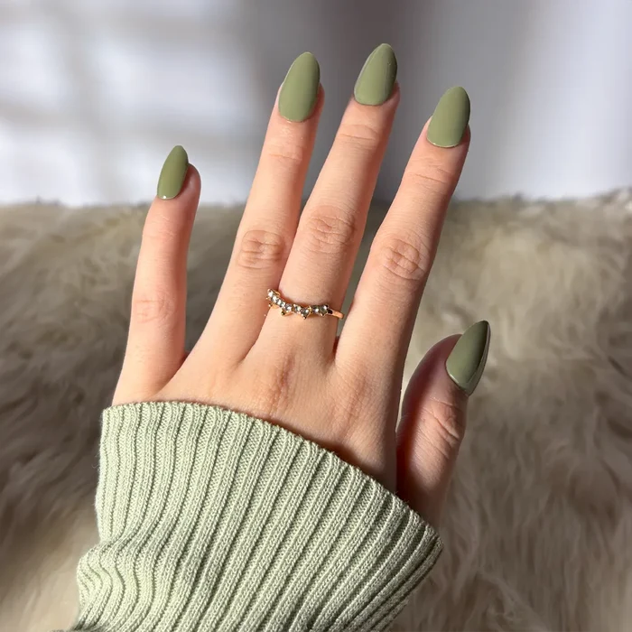 Hand with EyeCandys Avo-Cat-O Gel Nail Sticker – effortless 10-minute manicure in a muted avocado green, perfect for earthy, cozy vibes. Lasts 2–3 weeks, 7-free and allergy-friendly, cures under sunlight, ideal for minimalist spring or autumn nail looks with a soft matte finish.