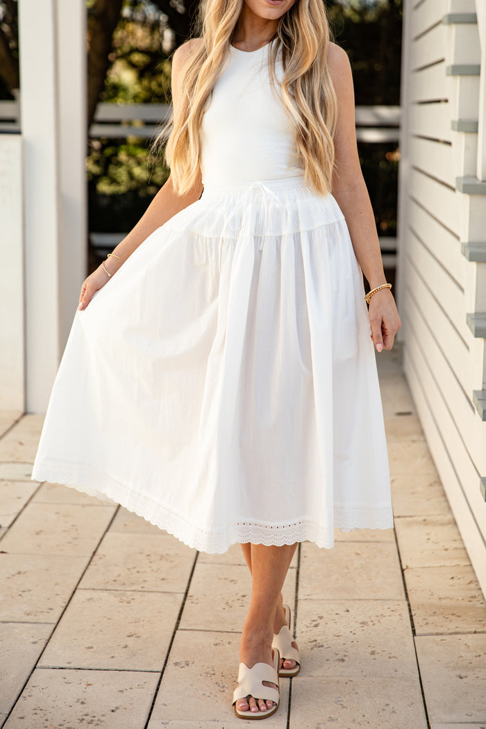 Woman wearing a white skirt standing on a wooden deck.