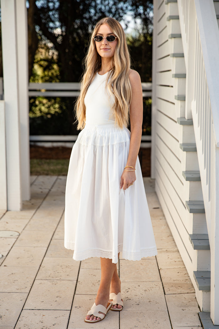 Woman wearing a white skirt standing on a wooden deck.