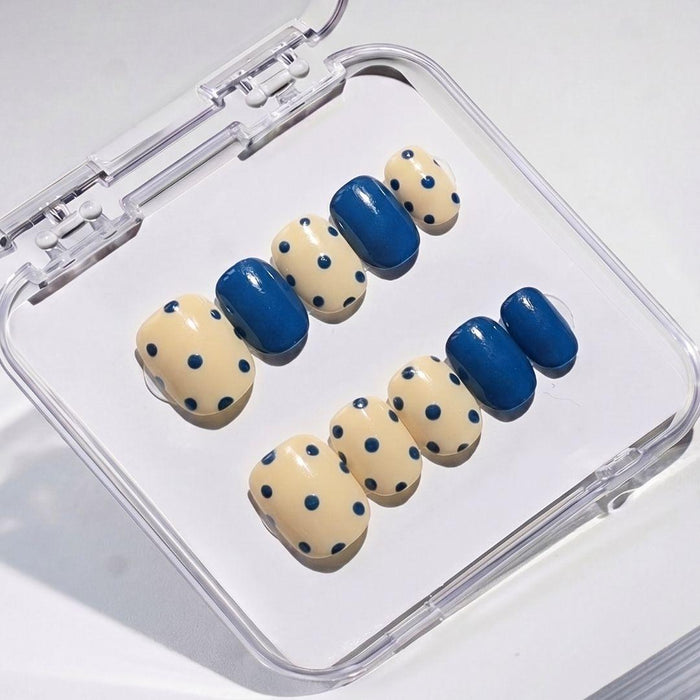 EyeCandys Sunny Side Up press on nails featuring butter yellow nails with navy polka dots and alternating solid glossy navy color block design.